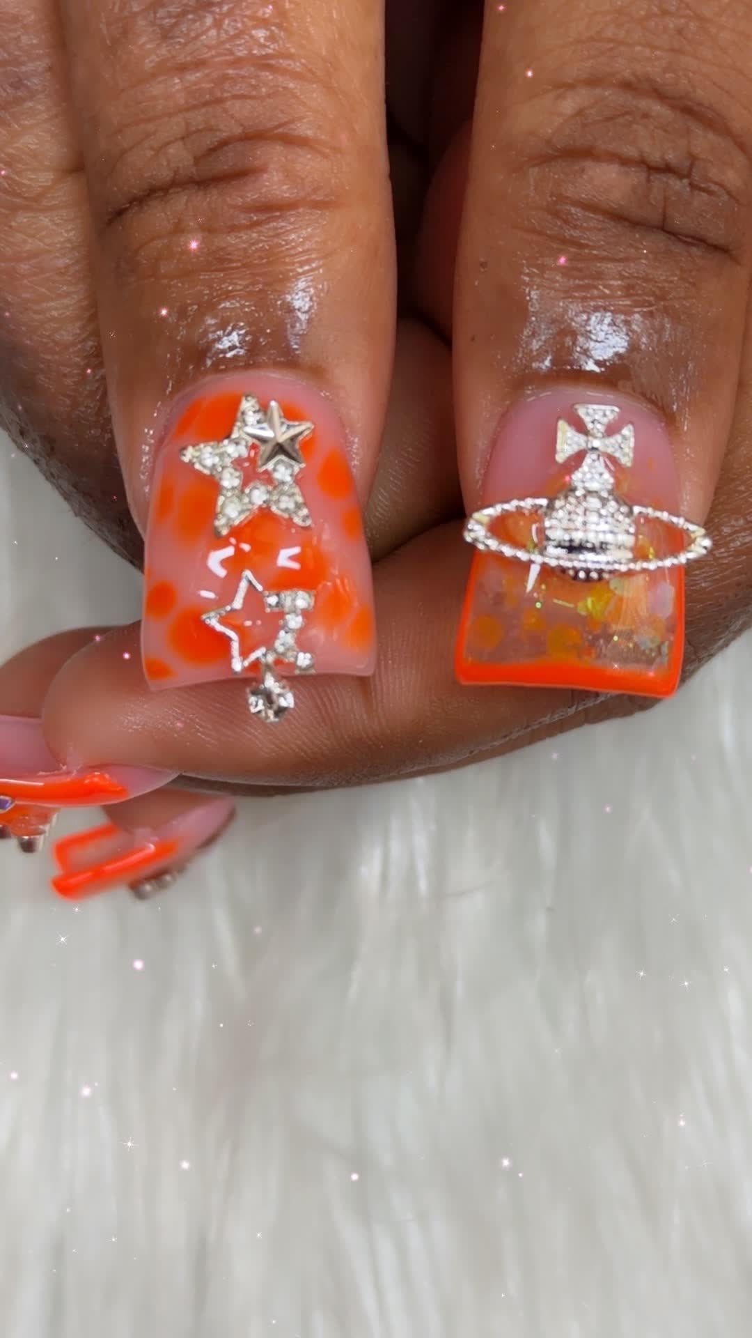Orange accent nails with star and orb charms